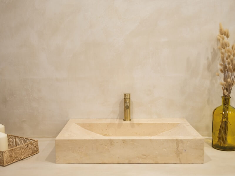 Béton ciré utilisé en faïence de salle de bain avec une vasque en travertin